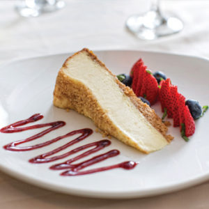 A slice of cheesecake and berries displayed on a white plate