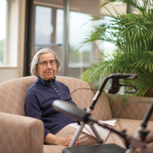 A senior woman relaxes on a sofa in a Whitney Center common room