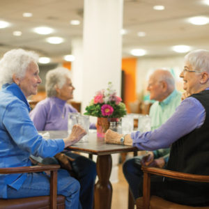 Three senior ladies and a senior man chat while sitting at a table in the Whitney Center Bistro