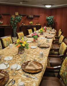 A long, formal dining room table, set for dinner