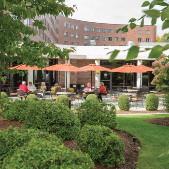 Several residents enjoying the outdoor patio terrace of Whitney Center