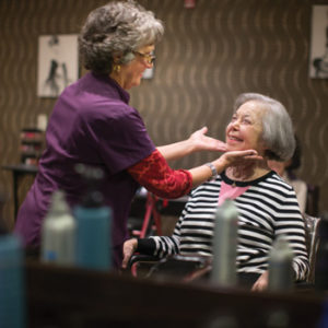 Female hair stylist touching up the hair of a senior woman