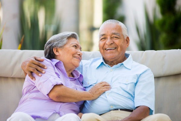 A well-dressed senior couple smile while posing for a photo