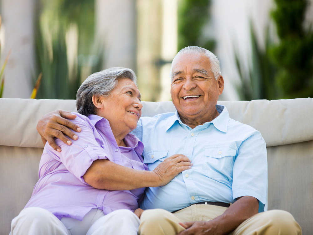 A well-dressed senior couple smile while posing for a photo