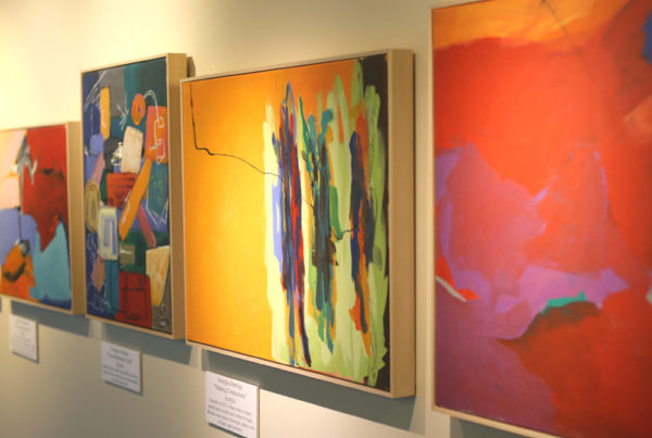 Four colorful framed art pieces displayed on a gallery wall