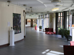 A hallway at Whitney Center, with works of art displayed on the walls, easels and pedestals