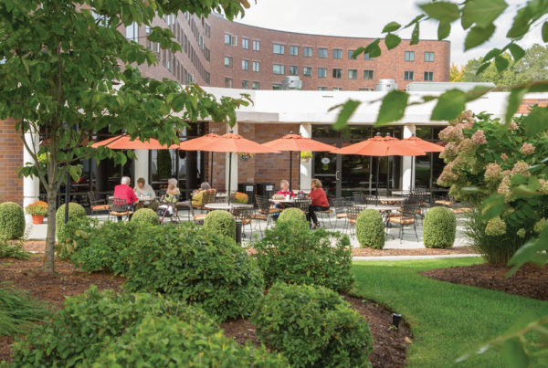 Several residents enjoying the outdoor patio terrace of Whitney Center