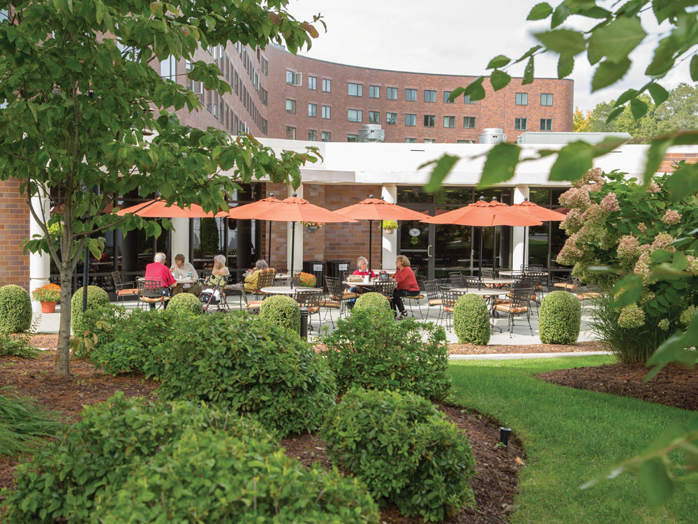 Several residents enjoying the outdoor patio terrace of Whitney Center