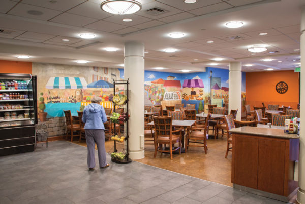 A senior woman picking out a piece of fruit at The Bistro, Whitney Center's casual and take-out dining cafeteria