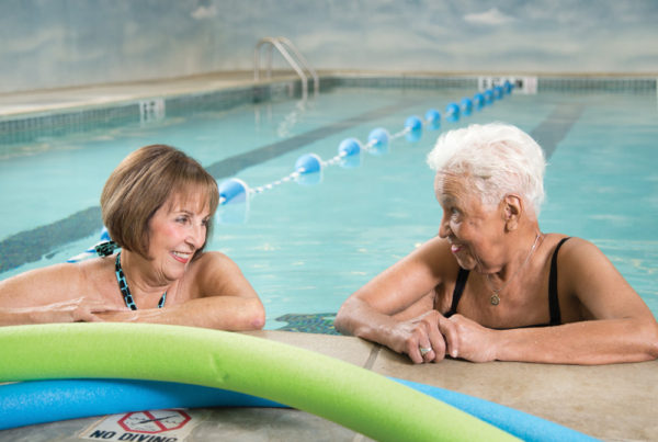 Two senior women relaxing in the water at the edge of a swimming pool