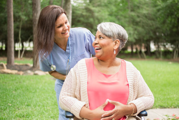 A medical staff member assists a middle-aged woman in a wheelchair