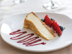 A slice of cheesecake and berries displayed on a white plate