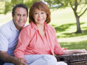 A senior couple with a picnic basket smile for a photo