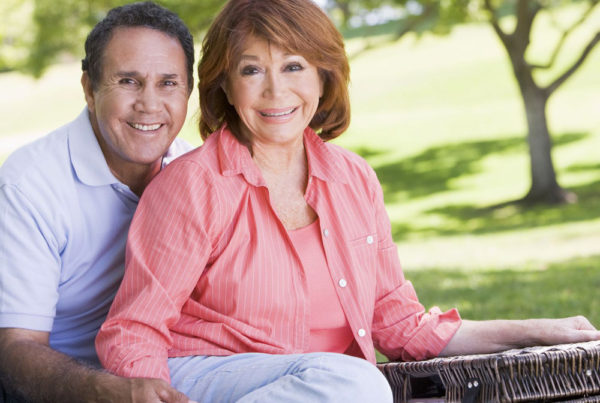 A senior couple with a picnic basket smile for a photo