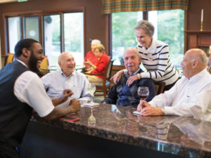 Four seniors gathered at a bar, having drinks and sharing a laugh with the bartender