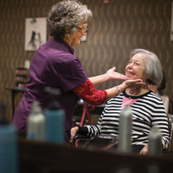 Female hair stylist touching up the hair of a senior woman