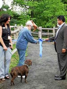 A senior woman cuts the ribbon to open a new walking trail