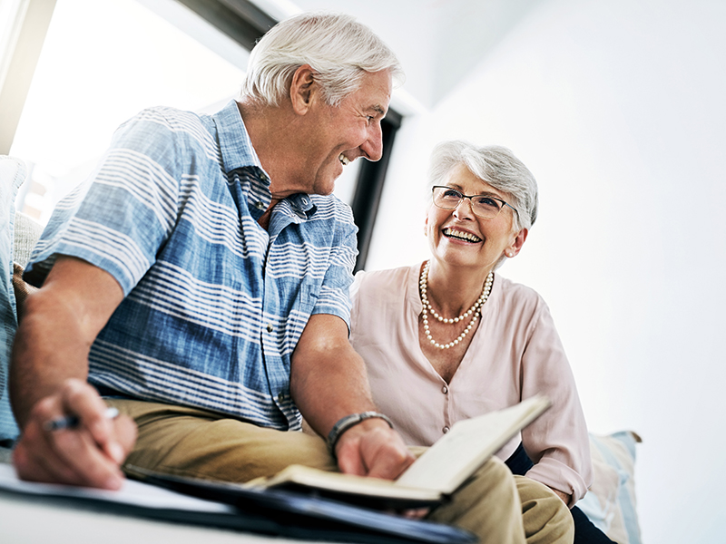 A senior couple smile as they write notes in a notebook